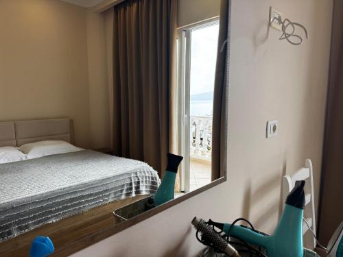 uno specchio in una camera da letto con un letto e una finestra di Light Apartment a Sarandë