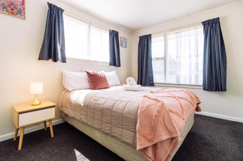 a bedroom with a bed and two windows at Belle Bonne Motel in Christchurch