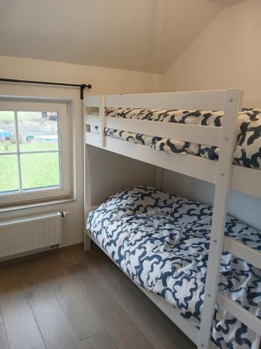 a bedroom with two bunk beds and a window at La petite maison de Terre de Partage in Ohey
