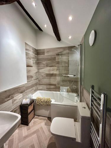 a bathroom with a tub and a toilet and a sink at Bakers Cottage in Cockermouth