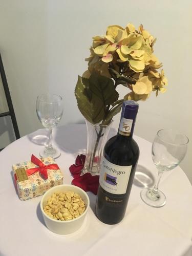 una mesa con una botella de vino y un jarrón con flores en Terraza Hotel Villavicencio en Villavicencio