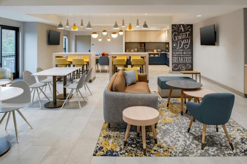 a living room with tables and chairs and a couch at TownePlace Suites by Marriott Portland Airport in Portland
