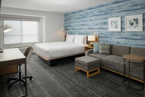 a hotel room with a bed and a couch at TownePlace Suites by Marriott Portland Airport in Portland