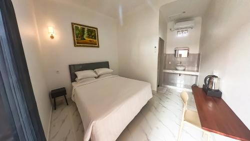a bedroom with a large white bed and a table at Arka Homestay Pesagi in Karangasem