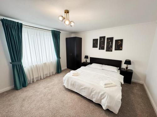 a bedroom with a large white bed with green curtains at Casa Paltinoasa in Păltinoasa