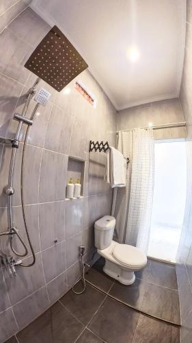 a bathroom with a white toilet and a shower at Arka Homestay Pesagi in Karangasem