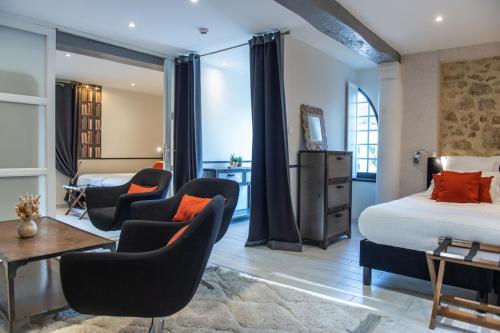 a hotel room with a bed and two chairs at Domaine de Larchey & son restaurant - Bordeaux Sud in Saint-Médard-dʼEyrans