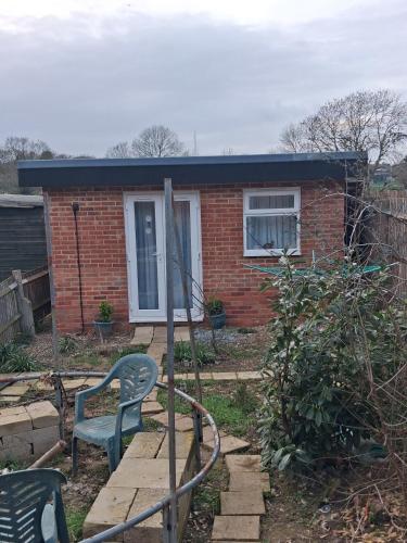 a small brick house with a green chair in the yard at Guest house in rear garden in Eltham