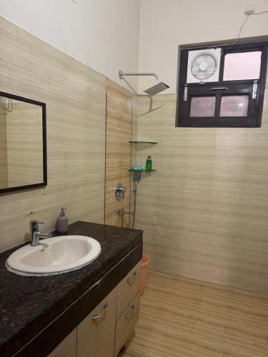 a bathroom with a sink and a shower with a window at Auranest Stays Duplex Home in Ludhiana