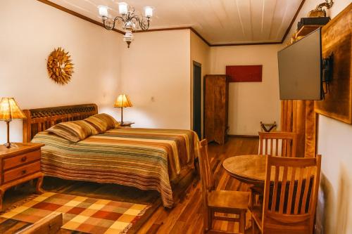 a bedroom with a bed and a table and chair at Tiradentes Pousada Ramalhete in Tiradentes