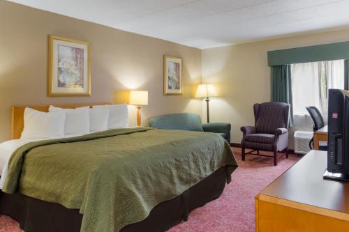 a hotel room with a bed and two chairs at All Seasons Inn & Suites Smithfield Providence in Smithfield