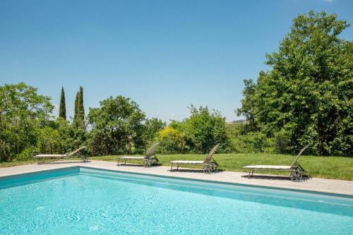 a swimming pool with three chaise lounges next to at Villa Beltramonto by MMega in Castiglioncello del Trinoro