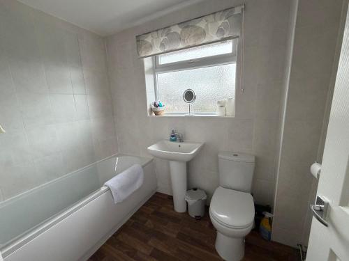 a bathroom with a toilet and a sink and a bath tub at Modern three bedroom home in Castle Donington in Castle Donington