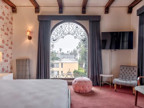 a room with a large window with a bed and a chair at Maison Twenty Seven in Los Angeles
