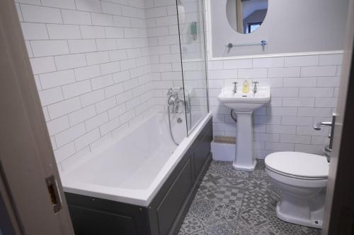 a bathroom with a tub and a toilet and a sink at The Milestone in Sowerby Bridge