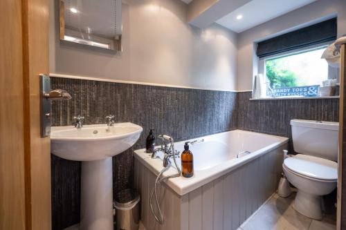 a bathroom with a sink and a tub and a toilet at No33 HILLVIEW LODGE BOUTIQUE COTTAGE in Brancaster