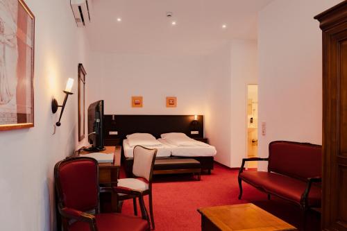 a hotel room with a bed and a chair at Hotel & Gasthaus Backmulde in Heidelberg