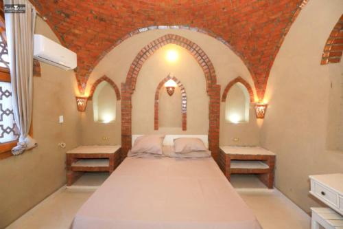 a bedroom with a large bed in a room with arches at Nefertari Palace apartments in Al Aqālitah
