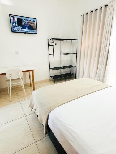 a white bedroom with a bed and a desk at Ap3 - Studio Confortável e Tranquilo in Guaíra
