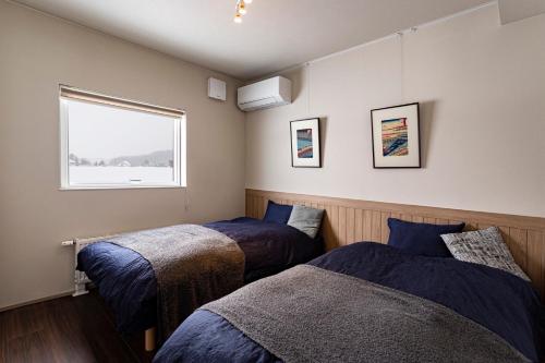 a bedroom with two beds and a window at Villa HIGASHIKAWA -Hokkaido- in Higashikawa