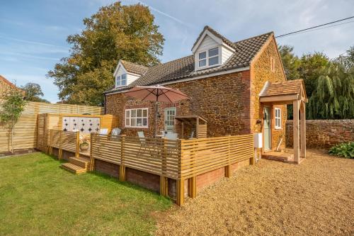 a house with a deck with an umbrella at No33 WOODLANDS BOUTIQUE COTTAGE in Heacham