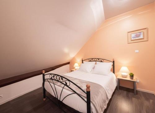 Un dormitorio con una cama con sábanas blancas y dos lámparas. en Le Cocooning, en Luxeuil-les-Bains
