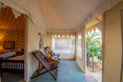 a room with a bed and a chair in a tent at Heritage Juma Resort with swimming pool in Jaisalmer