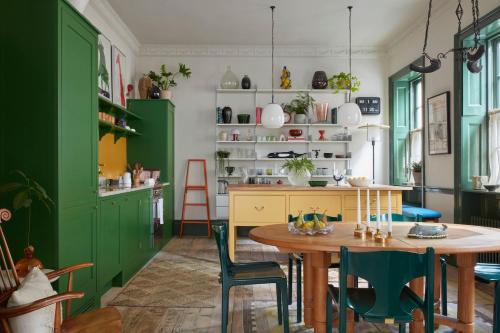 a kitchen with green cabinets and a table and chairs at 8 Holland Street Townhouse Bath in Bath