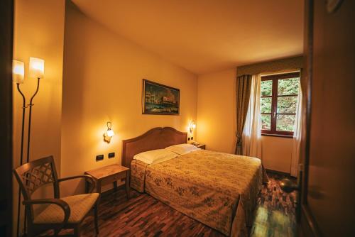 ein Schlafzimmer mit einem Bett, einem Stuhl und einem Fenster in der Unterkunft Hotel Camoretti in Almenno San Bartolomeo