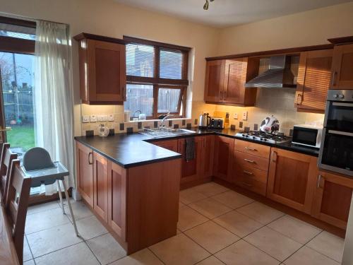 a large kitchen with wooden cabinets and a large window at Rostrevor Beach House in Rostrevor