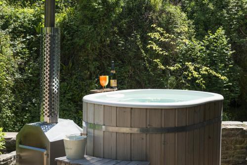 a jacuzzi tub with a glass of wine and a bottle of wine at Mill Cottage, Hanley Mill in Tenbury