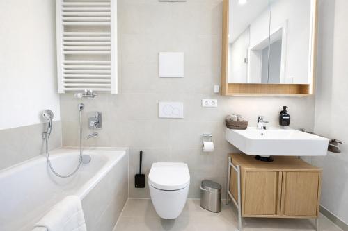 a bathroom with a sink and a toilet and a bath tub at TrulySpace - Modernes Apartment am Rathausplatz, Terrasse, Fahrstuhl in Augsburg