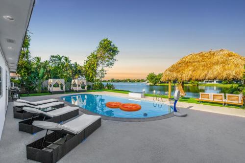 a swimming pool with chairs and a straw umbrella at Miami Paradise Waterfront Games in North Miami Beach