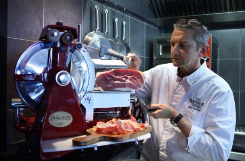 a man in a kitchen preparing meat in a machine at Hôtel Koh-I Nor by Les Etincelles in Val Thorens