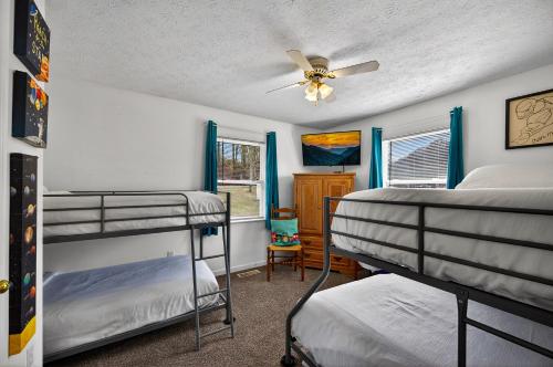 a bedroom with two bunk beds and a ceiling fan at Sunshine Cottage Hot Tub Game Room Grill MORE in Sevierville