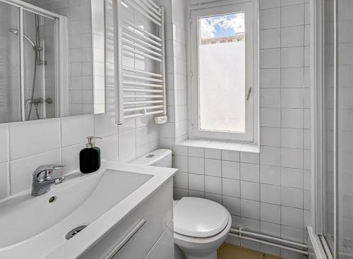 a white bathroom with a toilet and a sink at Superbe appartement au centre de POISSY in Poissy