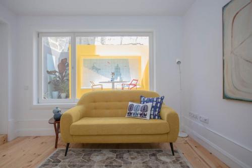 a yellow couch in a living room with a window at Liiiving in Porto - Clérigos Terrace Apartment in Porto