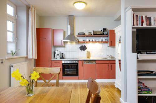 a kitchen with red cabinets and a vase of yellow flowers at Brauhaus am See in Gartow