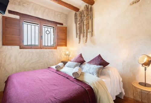 a bedroom with a bed with purple sheets and a window at El Kubo in Olba