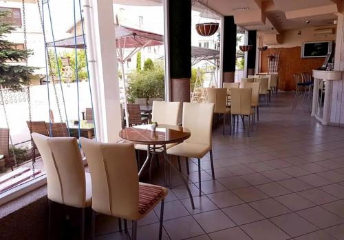 a restaurant with white chairs and tables and windows at Hotel Andre in Burgas