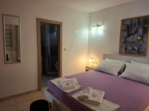a bedroom with a purple bed with towels on it at Apartman MAKA in Kučiće