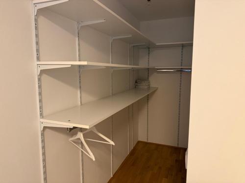 a walk in closet with white shelves and a wooden floor at QuietApt Vienna in Vienna