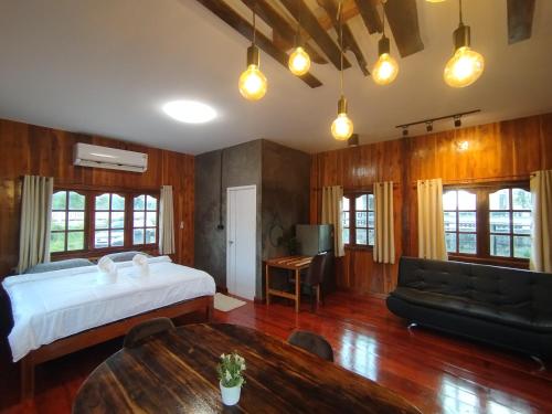 a bedroom with a bed and a couch and a table at บ้านพักมิตรภาพโฮมสเตย์ in Ban Choko