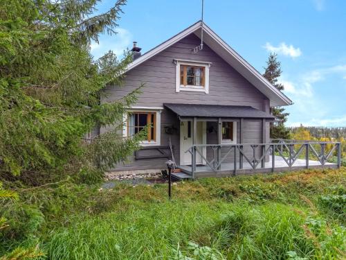 a gray house with a porch in the woods at Holiday Home Joutsen a by Interhome in Ruka