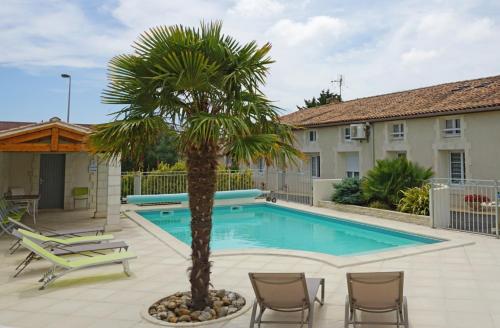 a palm tree and chairs next to a swimming pool at Studio à La Ferme in Sémussac