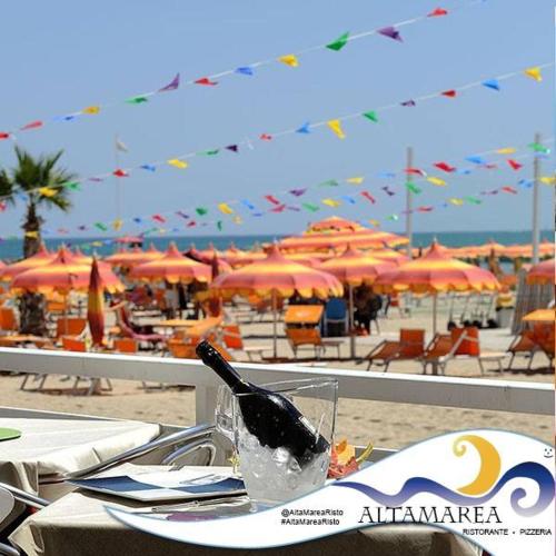 a table at the beach with a bottle on it at Hotel & Residence Cavalluccio Marino in Rimini