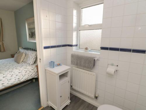 a small bathroom with a bed and a toilet at Sandy Cove in Chathill