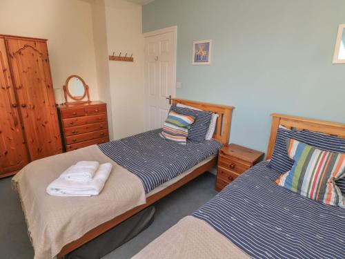 a bedroom with two beds and a dresser at Sandy Cove in Chathill