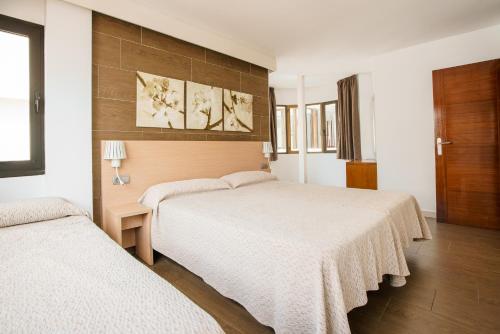 two beds in a hotel room with white sheets at Apartamentos San Francisco in San Antonio