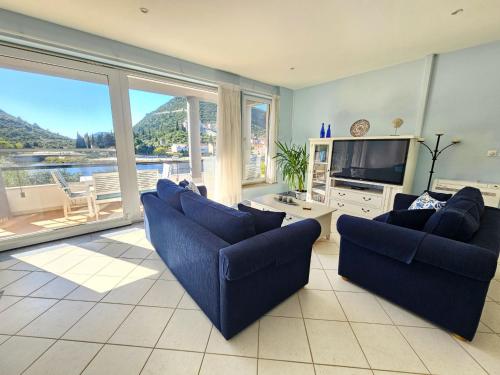 a living room with blue couches and a television at Apartment Waterfront Oasis-2 by Interhome in Mali Ston